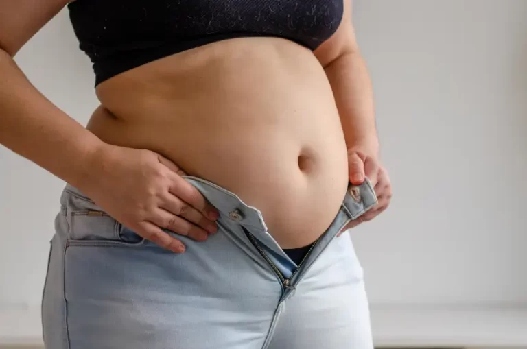 woman trying to zip pants over stomach